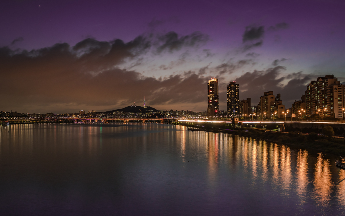 A wide shot of a city skyline behind a body of water at night