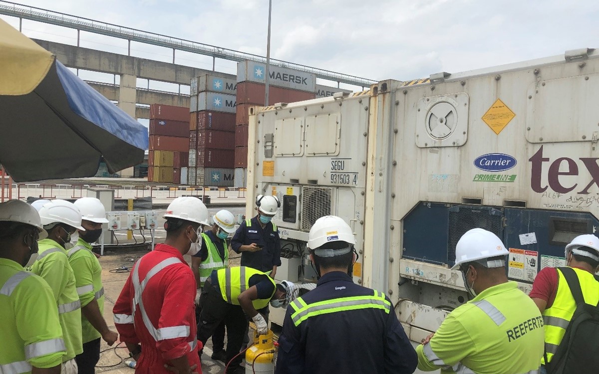A group of men in helmets standing around a yellow and silver cylinder