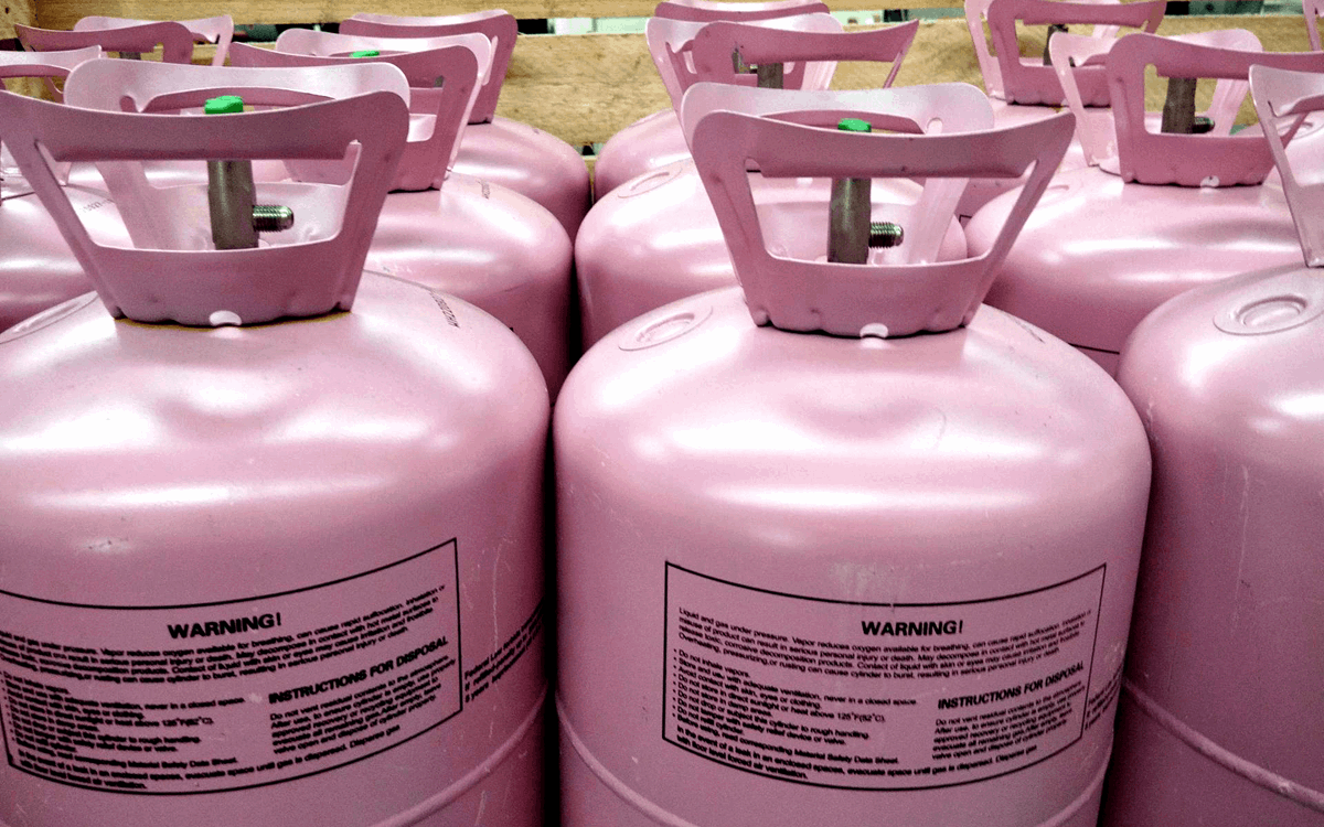 Close-up of rows of pink disposable cylinders in a wooden crate