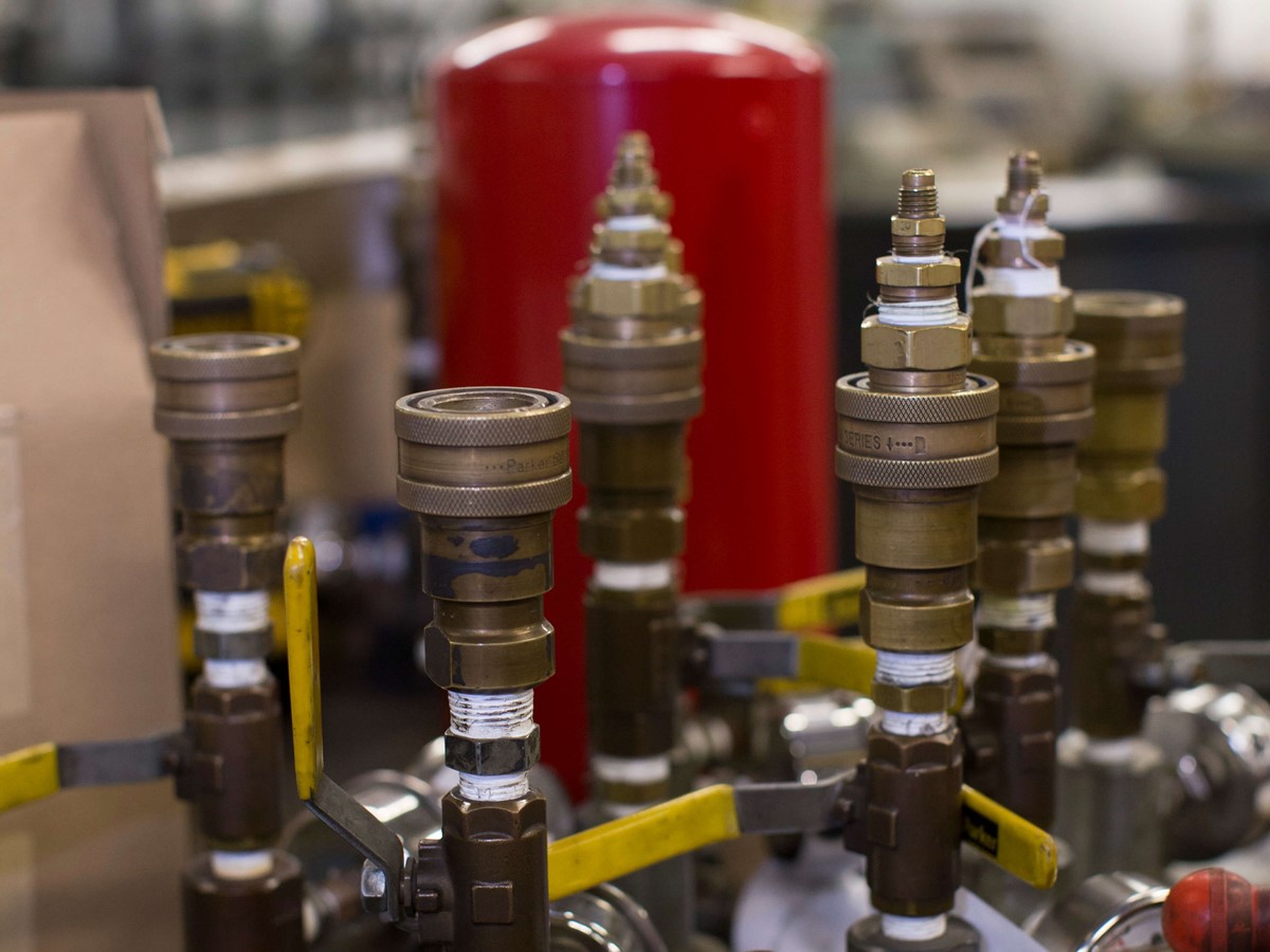 Cylinder valves sat on top of a table next to each other, they aren't connected to a cylinder