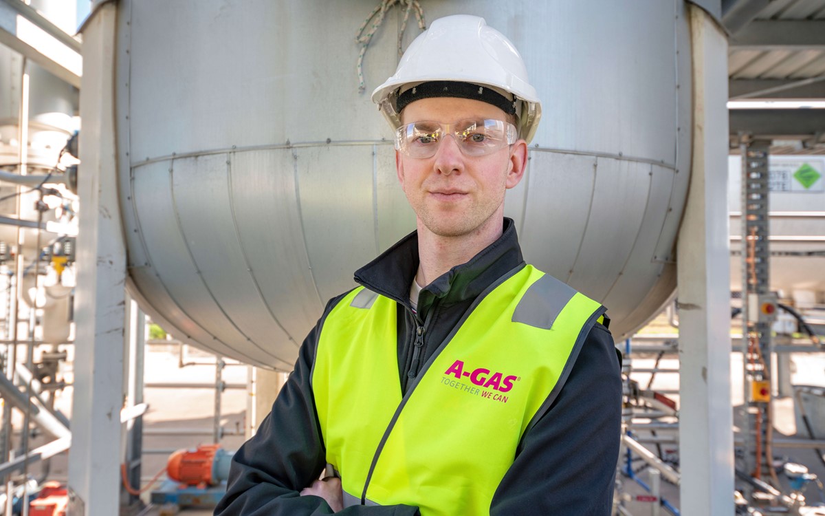 A man in a yellow high-vis jacket and safety helmet looking at the camera
