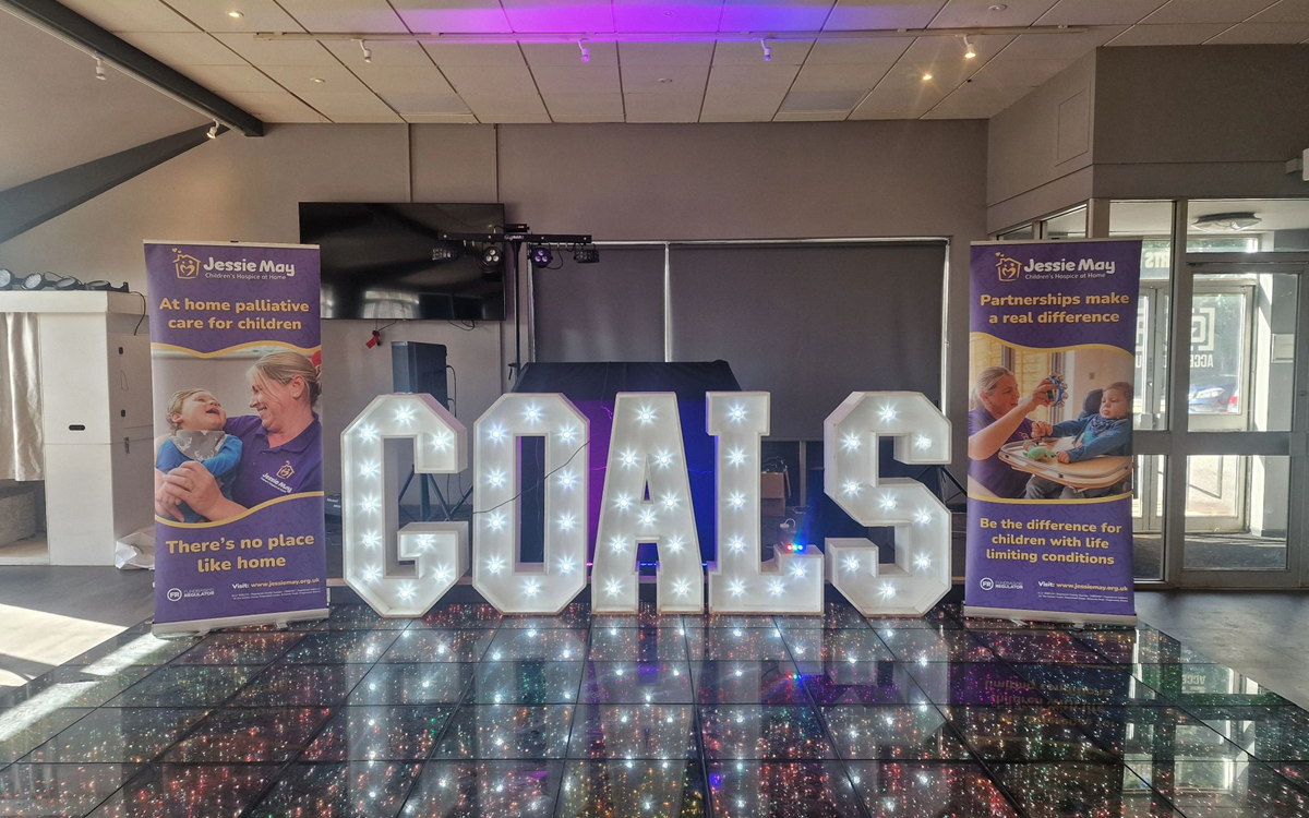 A three dimensional "Goals" logo between two purple banners on a stage